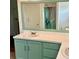 Bathroom with double vanity, mint green cabinets, framed mirror, and a shower with a patterned curtain at 873 United Se Ave, Atlanta, GA 30312