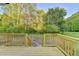 View of backyard from wood deck and stairs with forest background at 5825 Rolling Oaks Dr, Cumming, GA 30040