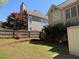 View of a fenced backyard featuring lush greenery, a retaining wall, and two-story home at 2325 Walnut Grove Way, Suwanee, GA 30024