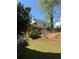Home's backyard featuring mature trees, terraced beds, and a grassy lawn at 2325 Walnut Grove Way, Suwanee, GA 30024