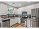 Well-lit kitchen with stainless steel appliances, white cabinets, granite countertops and a tile backsplash at 2325 Walnut Grove Way, Suwanee, GA 30024