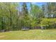 Spacious backyard with lush green grass, mature trees, trampoline and volleyball net at 12 Little Creek Manor Dr, Dallas, GA 30157