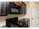 Galley kitchen featuring black appliances, granite countertops, and dark wood cabinets at 142 Susie Creek Ln, Villa Rica, GA 30180