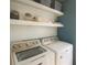 Bright laundry room featuring updated white machines and decorative floating shelves for storage and organization at 175 Diamond Ridge Ave, Canton, GA 30114