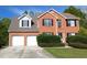Two story brick home featuring an attached two car garage, black shutters and well-manicured shrubs at 2432 Pendergrass Ln, Ellenwood, GA 30294