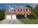 Two story brick home featuring an attached two car garage, black shutters and well-manicured shrubs at 2432 Pendergrass Ln, Ellenwood, GA 30294