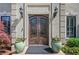 Elegant front entry with ornate double doors, flanked by potted plants, wall sconces, and detailed stonework at 18 Rose Gate Ne Dr, Atlanta, GA 30342