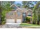 Two-story brick home featuring a two-car garage, well-manicured lawn, and mature trees in a suburban setting at 360 Beracah Sw Trl, Atlanta, GA 30331