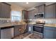 Modern kitchen featuring stainless steel appliances, gray cabinets, granite countertops, and mosaic backsplash at 8664 Spivey Village Trl, Jonesboro, GA 30236