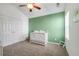 Bedroom with green accent wall, white crib, carpet flooring, and a window for natural light at 4510 Flowering Br, Powder Springs, GA 30127