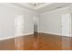 Spacious bedroom with hardwood floors, a tray ceiling, and multiple doors offering functionality and style at 113 Highgrove Pl, Mcdonough, GA 30253