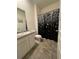 Bright bathroom with a sink and toilet featuring a black and silver shower curtain at 205 Sullivan St, Hampton, GA 30228