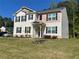 A two-story house features a green lawn, black shutters, and a combination of beige and tan exterior finishes at 205 Sullivan St, Hampton, GA 30228