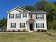 Charming two-story home featuring a manicured lawn and classic black shutters against a light beige and tan facade at 205 Sullivan St, Hampton, GA 30228