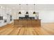 Spacious kitchen featuring a large central island with pendant lighting and hardwood floors throughout the space at 5130 Travers Ln, Cumming, GA 30040