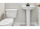 A pedestal sink and toilet in a light and airy bathroom; neutral color palette at 1085 Crown River Pkwy, Mcdonough, GA 30252