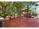 Backyard deck with a wooden pergola, bench seating, mature trees, and play area at 2648 Kenwood Dr, Duluth, GA 30096