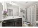 Well-lit bathroom features a dark vanity, framed mirror, decorative art, and shower-tub combination with patterned curtain at 2709 Kemp Court, Conyers, GA 30094