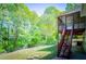A backyard view with wooden staircase and mature trees and green lawn at 4066 Harvest Ridge Dr, Douglasville, GA 30135