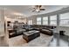 Cozy living room features a dark leather sectional, hardwood floors, and seamlessly connects to the open concept kitchen at 5525 Nesmith Ct, Cumming, GA 30040