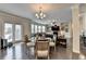 Bright dining area open to the living room, featuring hardwood floors, a chandelier, and glass table at 5525 Nesmith Ct, Cumming, GA 30040
