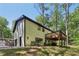 Stunning rear exterior featuring an elevated deck, bright siding, dark roof, and mature trees at 151 John Christopher Dr, Alpharetta, GA 30009