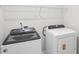 Bright laundry area featuring white appliances, upper shelving, and light walls at 7757 Sheffield Ter, Fairburn, GA 30213