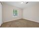 Bright empty bedroom features neutral walls, plush carpet, and a window with green scenery at 3690 Asbury Sw Ln, Atlanta, GA 30331
