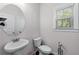 Half bathroom features a pedestal sink, toilet, window, and neutral wall color at 6424 Barker Station Walk, Sugar Hill, GA 30518