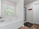 Well-lit bathroom featuring a soaking tub with large window and separate glass shower at 6424 Barker Station Walk, Sugar Hill, GA 30518