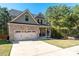 Attractive home featuring a brick facade, two-car garage, long driveway, and well-maintained landscaping at 6424 Barker Station Walk, Sugar Hill, GA 30518