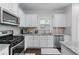 Kitchen features stainless appliances, granite countertops, and white cabinets, complete with modern fixtures at 6424 Barker Station Walk, Sugar Hill, GA 30518