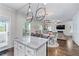 Open floor plan showing kitchen with island, dining area, and living room with fireplace and large windows at 6424 Barker Station Walk, Sugar Hill, GA 30518