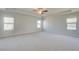 A bright main bedroom with a tray ceiling, fan, and large windows for ample natural light at 2366 Cadenza Cir, Dacula, GA 30019