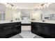 Bright main bathroom with double sinks, a vanity with dark cabinets, tiled floor, and views into the main bedroom at 4435 Bellwood Cir, Atlanta, GA 30349