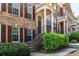 Close-up of a brick townhome with dark shutters, a covered entrance, and lush greenery at 2145 Shoop Se Ct # 3, Smyrna, GA 30080