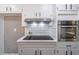Updated kitchen with stainless steel oven, cooktop, white cabinets, subway tile backsplash, and modern vent hood at 714 Lanford Springs Sw Dr, Lilburn, GA 30047