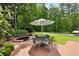 Charming backyard with brick patio, jacuzzi, and an umbrella-covered dining set, perfect for outdoor gatherings at 8925 Huntcliff Lake Ct, Atlanta, GA 30350
