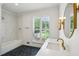 Well-lit bathroom with hexagon tile flooring, soaking tub, and a large vanity with brass accents at 8925 Huntcliff Lake Ct, Atlanta, GA 30350