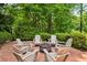 Cozy outdoor fire pit area with Adirondack chairs on a brick patio surrounded by green foliage at 8925 Huntcliff Lake Ct, Atlanta, GA 30350