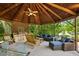 Spacious outdoor kitchen and lounge area with comfortable seating and a built-in grill under a wooden gazebo at 8925 Huntcliff Lake Ct, Atlanta, GA 30350