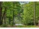 Scenic view of a serene pond surrounded by lush greenery and mature trees at 8925 Huntcliff Lake Ct, Atlanta, GA 30350