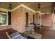 Spacious covered front porch with outdoor seating and brick walls with decor and black shutters at 107 Estates At The Lake Dr, Canton, GA 30114