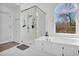 Bright main bathroom featuring a glass shower, soaking tub, and large window at 2433 Idlewood Way, Snellville, GA 30078