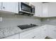 Detailed view of kitchen elements, including granite countertops, cooktop, and stainless steel microwave at 247 Lotus Ln, Covington, GA 30016