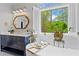 Bright bathroom featuring modern vanity, soaking tub with gold faucet, a plant, and window with beautiful outdoor view at 300 Brayward Chase, Roswell, GA 30076