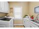 Well-lit laundry room with white cabinets, a sink, and modern washer and dryer for efficient chores at 300 Brayward Chase, Roswell, GA 30076