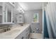 Well-lit bathroom featuring a double vanity, a large mirror, and a shower with blue tiling at 6500 Chickasaw Dr, Douglasville, GA 30135
