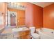 Bathroom with vanity, framed mirror, tub, and toilet. Bedroom visible through doorway at 5679 Windfall Ln, Lithonia, GA 30058