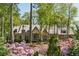 Elegant stone home with a distinctive roofline, surrounded by vibrant azaleas and mature trees at 105 Kingston Mnr, Atlanta, GA 30342